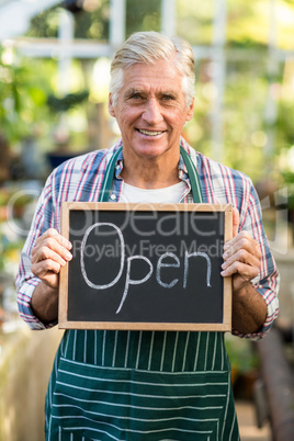 Happy mature owner holding open sign placard