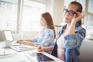 Portrait of young businesswoman with colleague at desk in office