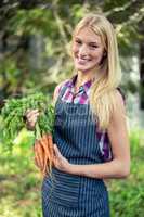 Portrait of happy gardener with carrots at garden