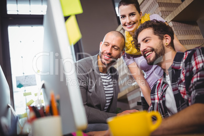 Happy coworkers at computer desk in office