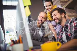 Happy coworkers at computer desk in office