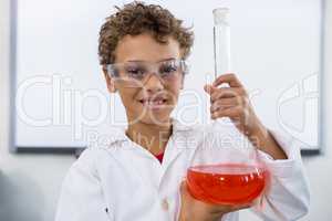 Boy holding flask with liquid at laboratory in school