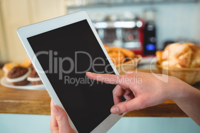 Close-up of barista finger scrolling tablet pc at cafe