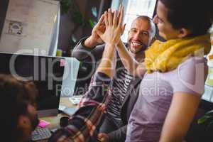 Creative coworkers high fiving in office