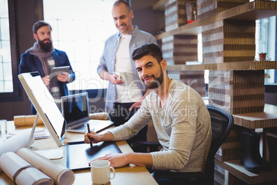 Creative businessman using graphic tablet at computer desk