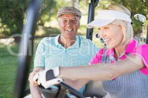 Mature couple enjoying in golf buggy