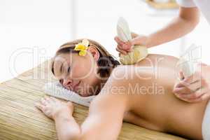 Relaxed woman receiving herbal compress massage