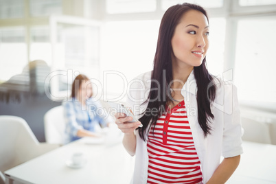 Young businesswoman holding mobile phone at creative office