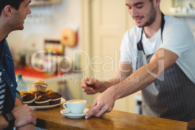 Barista giving coffee to customer at cafe