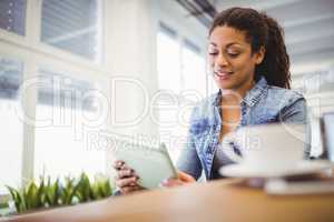 Businesswoman using digital tablet while sitting in creative off