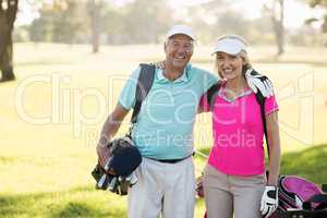 Happy mature golfer couple with arm around