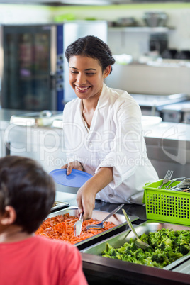 Smiling woman serving food to schoolboy