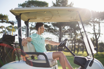 Side view of smart man sitting in golf buggy