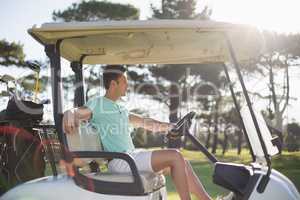 Side view of smart man sitting in golf buggy