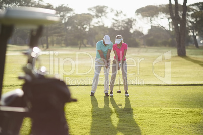 Full length of man teaching woman to play golf