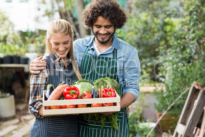 Smiling couple holding vegetables crate