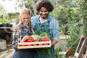 Smiling couple holding vegetables crate