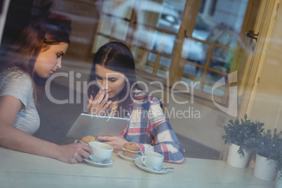 Young women looking at tablet computer in coffee house