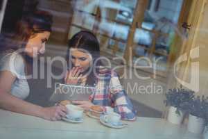 Young women looking at tablet computer in coffee house