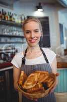 Portrait of happy waitress offering breads in coffee shop