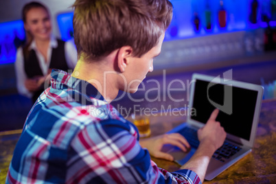 Man using laptop on counter with bartender standing