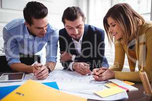 Businesswoman with coworkers discussing on blueprint