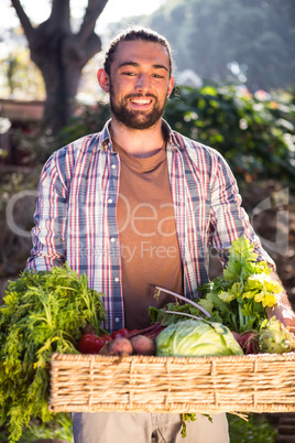 Happy hipster gardener holding fresh vegetables at garden