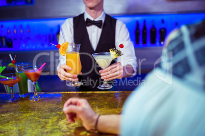 Bartender serving cocktail to woman
