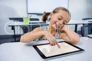 Happy girl using digital tablet in classroom
