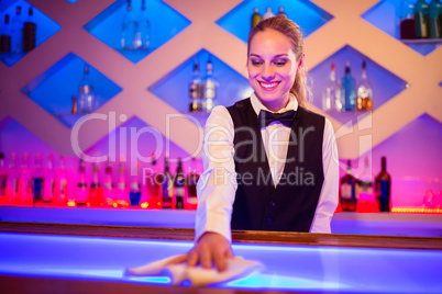 Barmaid smiling cleaning bar counter