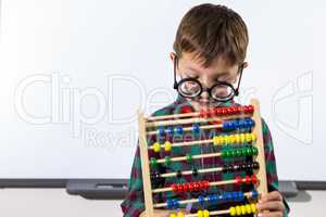 Cute boy playing with abacus in classroom