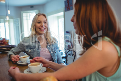 Happy customers communicating at counter in coffee shop
