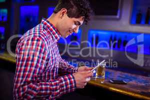 Smiling man using digital tablet by bar counter
