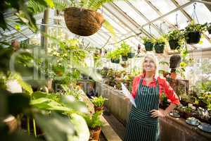 Woman looking at plants hanging in greenhouse