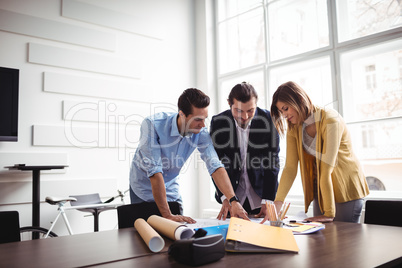 Businessman explaining blueprint to coworkers