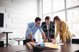 Businessman explaining blueprint to coworkers