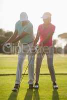 Full length of mature male golf player teaching woman