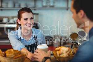 Happy barista offering coffee to customer at cafe