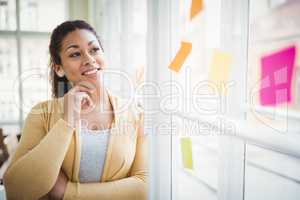 Thoughtful businesswoman looking at adhesive notes in creative o