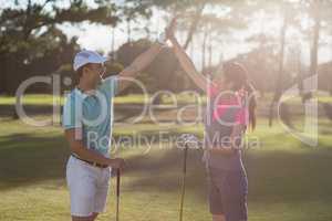 Smiling golf player couple giving high five