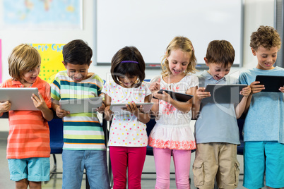 Smiling schoolchildren using digital tablet