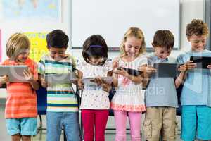 Smiling schoolchildren using digital tablet