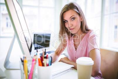 Portrait of confident businesswoman sitting at desk in office