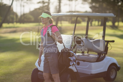 Woman standing by golf buggy