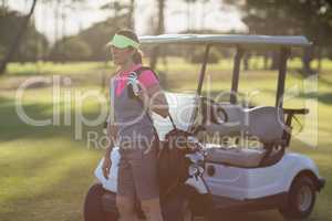 Woman standing by golf buggy