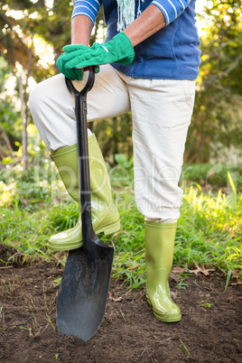 Low section of gardener standing with shovel at garden