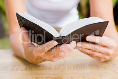 Midsection of woman reading bible