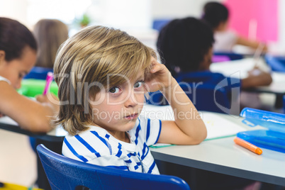 Serious boy with classmates in classroom