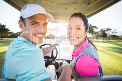 Cheerful golfer couple sitting in golf bugggy