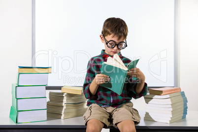Boy reading book while sitting in classroom